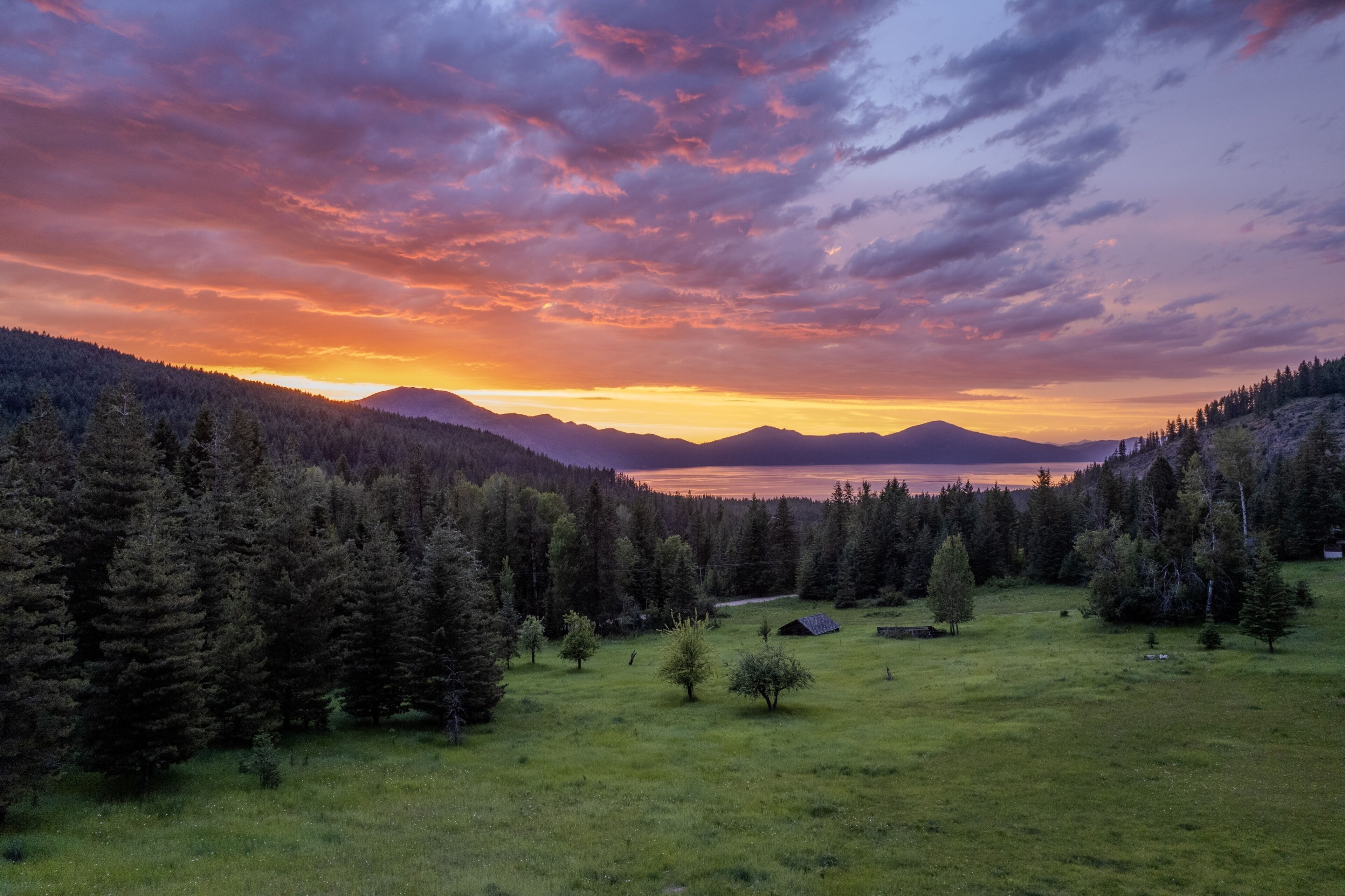 A summer sunset over forest and meadow in the Hayden area. Onyx & Oak Homes builds custom homes in Hayden, Idaho.