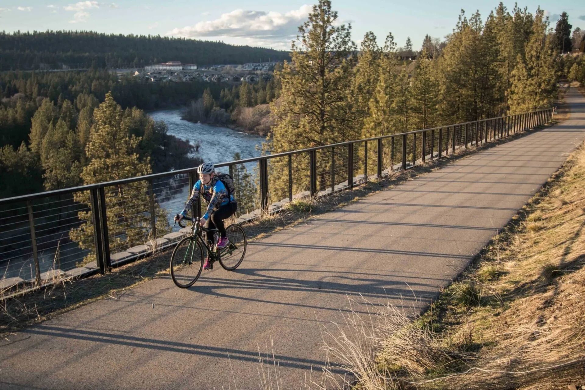 A cyclist on the Centennial Trail above the Spokane River. Onyx & Oak Homes builds custom homes in Spokane Valley, Washington.